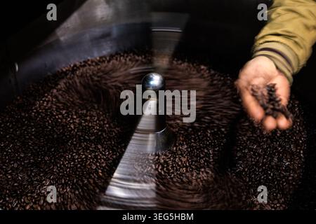 Una torrefazione artigianale controlla i chicchi appena tostati in un vassoio di raffreddamento circolare per garantire una qualità eccellente durante il processo di produzione. Foto Stock