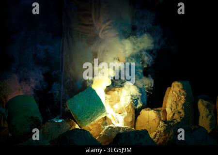 Un operaio della fonderia versa con cura il metallo fuso in uno stampo di sabbia mettendo in risalto l'artigianato metallurgico tradizionale e i fabbrici industriali Foto Stock