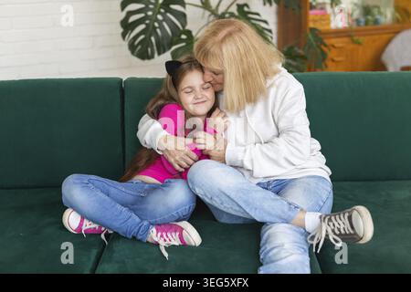 Buona nipote e nonna seduta sul divano in posa divertente. Nonna divertirsi con il nipote a casa. Persone anziane, famiglia e generazione co Foto Stock