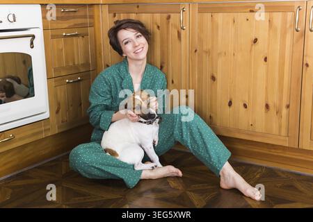 Giovane donna con un cane carino Jack russell terrier seduto sul pavimento. Animali domestici e casa. Resta a casa Foto Stock