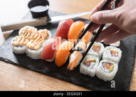 Donna che mangia sushi con le bacchette a casa Foto Stock