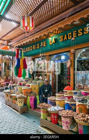 L'uomo siede nel suo vivace negozio di spezie a Marrakech, in Marocco Foto Stock