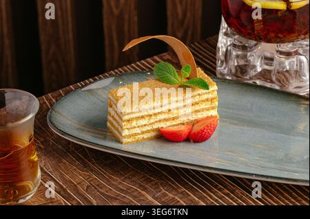 Fetta di torta al miele con fragole e tè Foto Stock