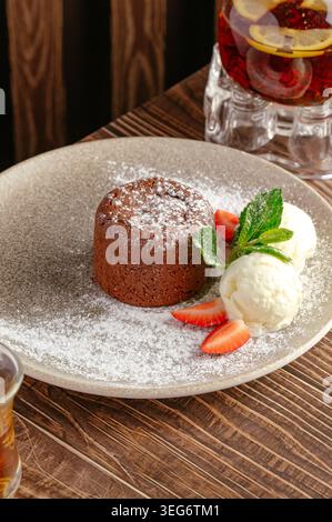 Torta di lava al cioccolato calda con gelato e fragole Foto Stock