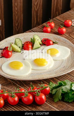 Tre uova fritte con il lato soleggiato e insalata fresca Foto Stock