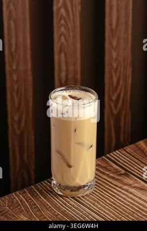 Un alto bicchiere di caffè ghiacciato su un tavolo di legno scuro Foto Stock