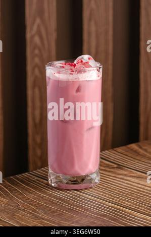 Latte rosa ghiacciato con punte di lampone su legno Foto Stock