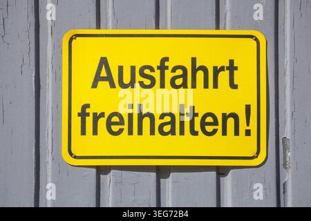 Gelbes Schild Ausfahrt freihalten an einem grauen Tor, Deutschland Foto Stock