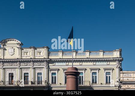 Edificio storico con bandiera Ucraina che sventola sul cielo blu. Dettagli architettonici e simbolo nazionale Foto Stock