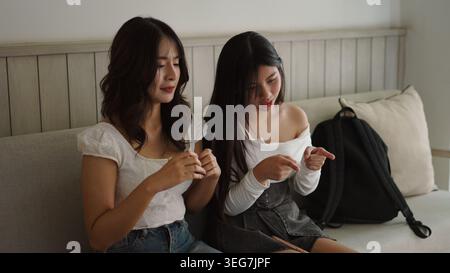Giovani donne asiatiche amici seduti sul divano condividere momento e interagire Foto Stock