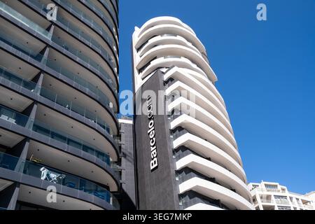 Vista ad angolo basso dei moderni e alti edifici di appartamenti con balconi sovrapposti, facciate curve e un cielo azzurro limpido a Sliema, Malta, 5 agosto 2025. TH Foto Stock