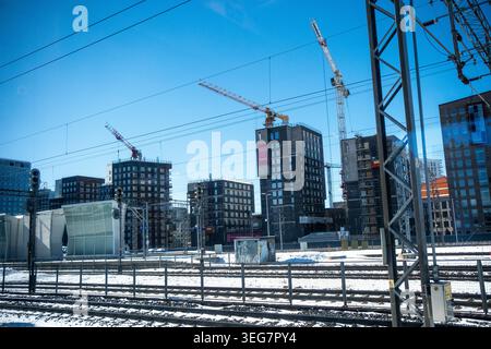 Edifici residenziali in costruzione sorgono a Pasila oltre i numerosi binari ferroviari innevati e le linee elettriche aeree, Helsinki, Foto Stock