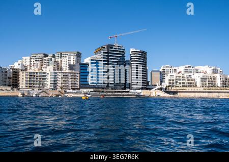 Vista sull'acqua del porto del moderno skyline sul lungomare con torri di appartamenti e sul Mar Mediterraneo a Sliema, Malta, 5 agosto 2025. L'im Foto Stock