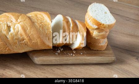 Fette di baguette appena tagliate su un asse di legno. Pane fresco a fette. Pane rustico di segale fatto a mano con crosta dorata e briciole morbide è perfetto per Foto Stock
