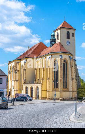 La chiesa di San Giacomo il Vecchio si erge a Boskovice. La gente passava per la strada acciottolata. La luce del sole splende sull'edificio colorato durante una giornata limpida. Foto Stock