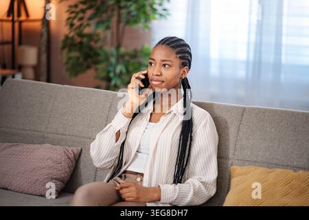 Giovane donna nera che parla con lo smartphone a casa Foto Stock