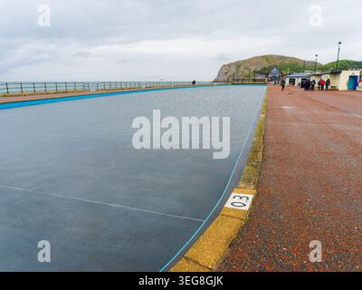Llandudno, Galles, Regno Unito, 16 maggio 2026, Llandudno piscina e passeggiata in una giornata nuvolosa, mostrando il lungomare con la montagna Great orme nel bac Foto Stock