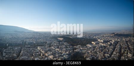 Un ampio panorama aereo cattura il paesaggio urbano densamente popolato di Atene in Grecia sotto un cielo azzurro, con l'iconica Acropoli visibile Foto Stock