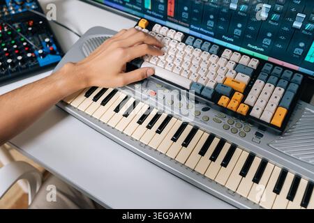 Vista dall'alto del tecnico del suono che lavora alla produzione musicale in studio domestico, riproduce la tastiera e mixa tracce audio su una workstation audio digitale con Foto Stock