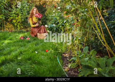 Donna felice che tiene in mano un fresco bouquet Dahlia nel giardino del cortile Foto Stock
