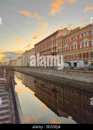 Russia, San Pietroburgo, 30 marzo 2025: Pittoresco argine al tramonto, riflesso a specchio sulla superficie piana dell'acqua del canale Griboyedov Foto Stock