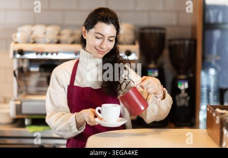 Barista in grembiule rosso per preparare caffè Foto Stock