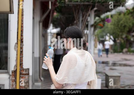 Donna che beve acqua da una bottiglia di plastica, movimento non posto, movimento naturale naturale, profilo laterale Foto Stock