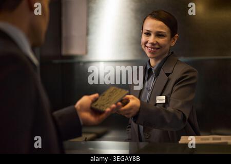 Il receptionist dell'hotel per adulti consegna la chiave a un uomo d'affari Foto Stock