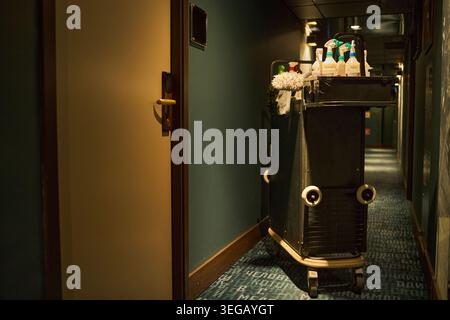 Carrello del servizio dell'hotel parcheggiato nel corridoio per le operazioni di pulizia della camera Foto Stock