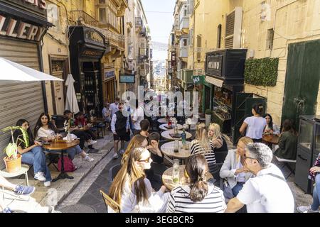 La Valletta, Malta, 3 aprile 2024. turisti seduti tra i tavoli di un bar nei vicoli stretti del centro storico della città Foto Stock