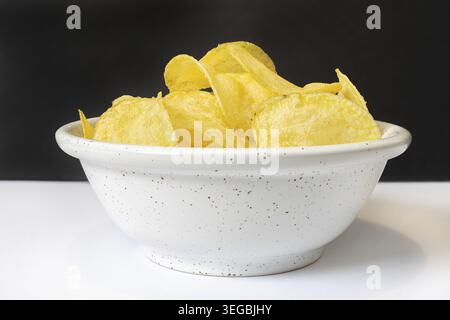 Spuntini croccanti di patate serviti in una ciotola bianca Foto Stock