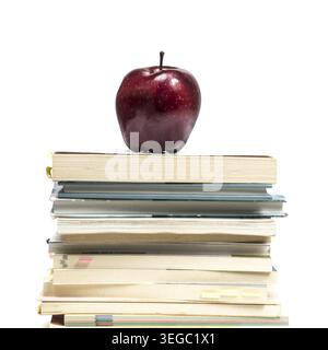 Una mela rossa in cima a una pila di libri Foto Stock