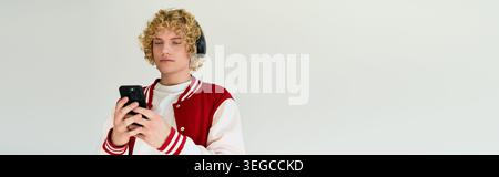 Un giovane dai capelli biondi in abiti casual si sposa con lo stile moderno in uno spazio studio, banner Foto Stock