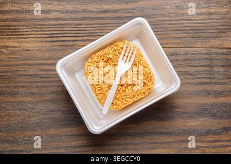 Spaghetti istantanei essiccati e forchetta monouso bianca in piastra di plastica Foto Stock