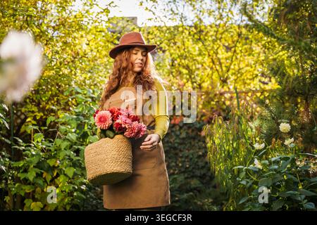 Donna dai capelli rossi sorridente seduta nell'Enchanted Autumn Garden Foto Stock
