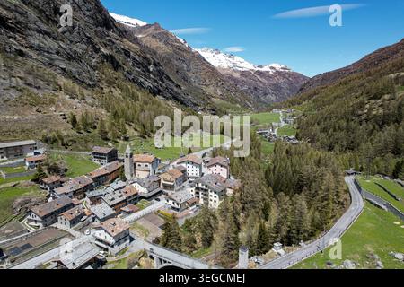Vista aerea del villaggio alpino di Valgrisenche con case in pietra e una torre di chiesa annidata in una profonda valle circondata da aspre montagne Valgris Foto Stock