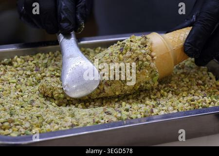 Un gelato arabo cono di ashta arrotolato in pistacchi frantumati. Foto Stock