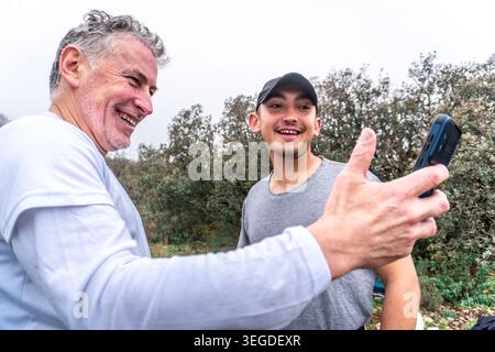 Uomini allegri che ridono scattando selfie all'aperto Foto Stock