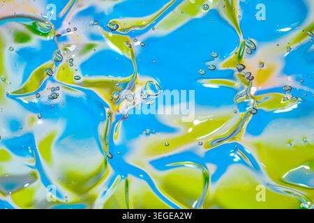 Foto macro astratta di gel cosmetico trasparente con bolle su sfondo blu e verde colorato, ideale per la cura della pelle e l'idratazione Foto Stock