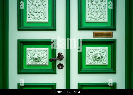 Primo piano di un'elegante porta in legno verde con pannelli decorativi a rilievo, maniglia antica e design classico, Liepaja, Lettonia Foto Stock
