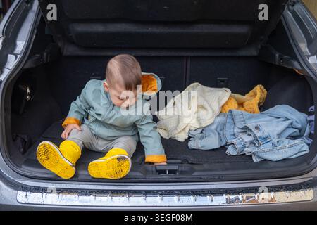 Bambino seduto nel bagagliaio aperto del garage Foto Stock