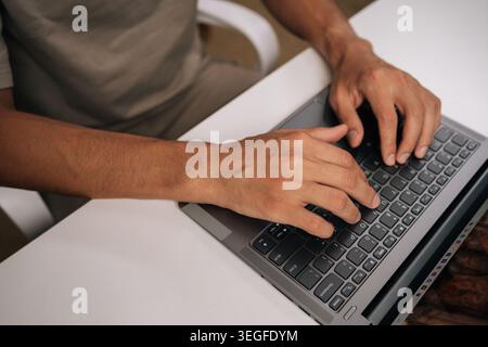 Immagine ritagliata del codice di digitazione maschile del programmatore sulla tastiera del notebook, che mostra il processo di sviluppo software e l'esperienza di codifica, primo piano. Foto Stock