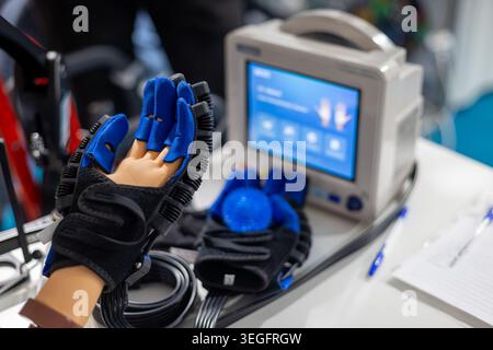 Dispositivo robotizzato per la riabilitazione delle mani con guanti per terapia. Primo piano di un guanto per riabilitazione robotizzato su un modello manuale con comandi terapeutici, cavi e. Foto Stock