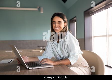 Ritratto di una donna d'affari seduta sulla scrivania che lavora con un computer portatile Foto Stock