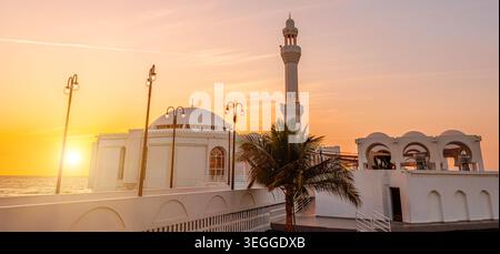 Il sole tramonta sulla Moschea al Rahmah sul lungomare di Jeddah con l'edificio JYC Jeddah Yacht Club, sulla costa del Mar Rosso dell'Arabia Saudita, al tramonto Foto Stock