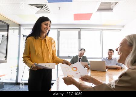 Donna d'affari che distribuisce documenti durante la riunione dell'ufficio aziendale Foto Stock