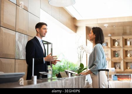 Receptionist maschile che assiste gli ospiti dell'hotel alla reception Foto Stock