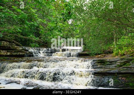 Le cascate d'acqua si estendono su rocce in una serie di piccole cascate, incorniciate da una vegetazione lussureggiante nel paesaggio colombiano. Foto Stock