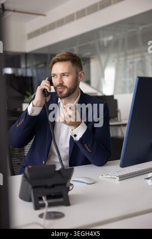Un giovane uomo d'affari che parla seriamente al telefono fisso Foto Stock