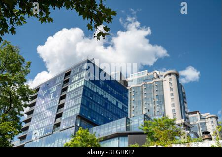 Edificio di appartamenti a più piani vicino ad un parco municipale sotto la luce del giorno. Concetto di pianificazione municipale sostenibile, sviluppo della comunità ed ecologia Foto Stock